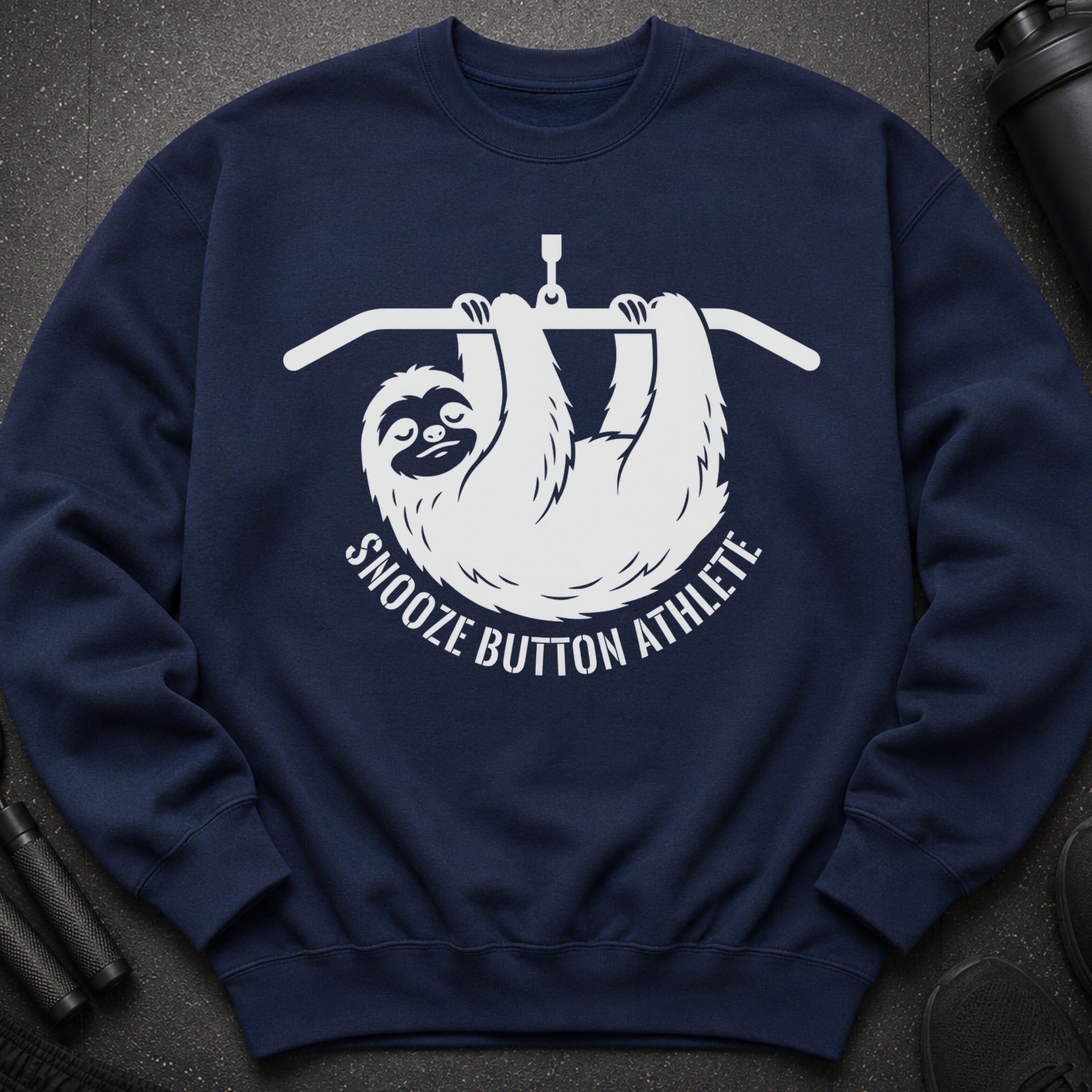Navy sweatshirt with white graphic of a sloth hanging from a bar, reading "Snooze Button Athlete".