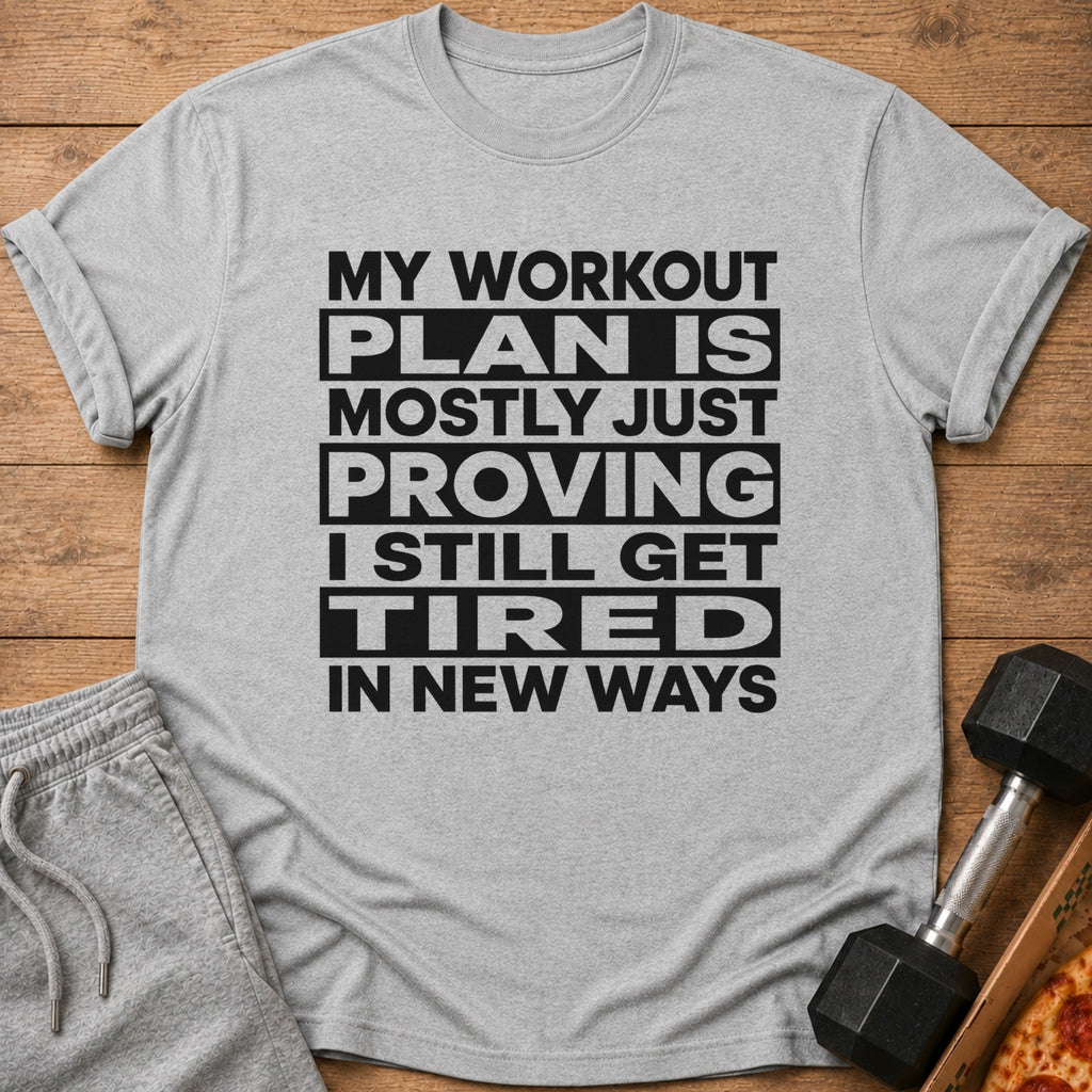 Grey t-shirt with black text: "MY WORKOUT PLAN IS MOSTLY JUST PROVING I STILL GET TIRED IN NEW WAYS".