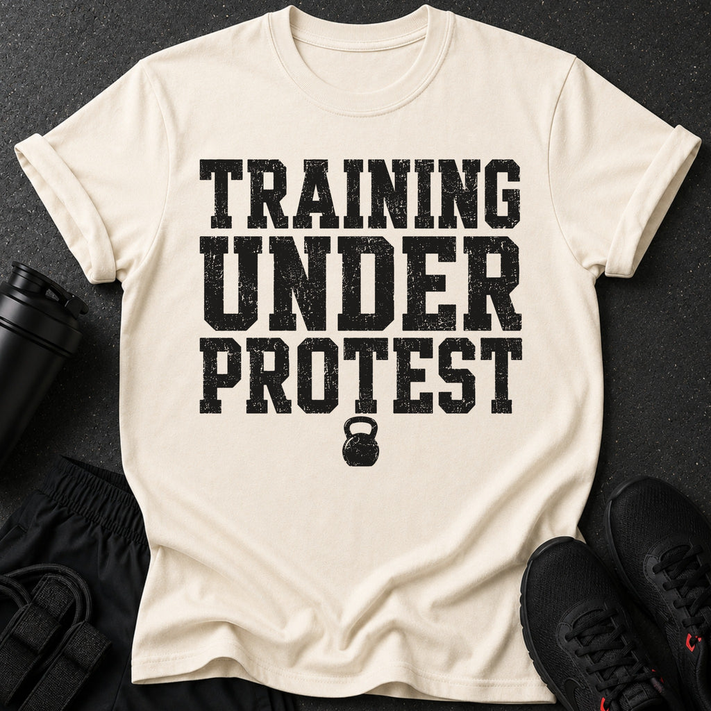 Cream t-shirt with black distressed text "TRAINING UNDER PROTEST" and kettlebell graphic.