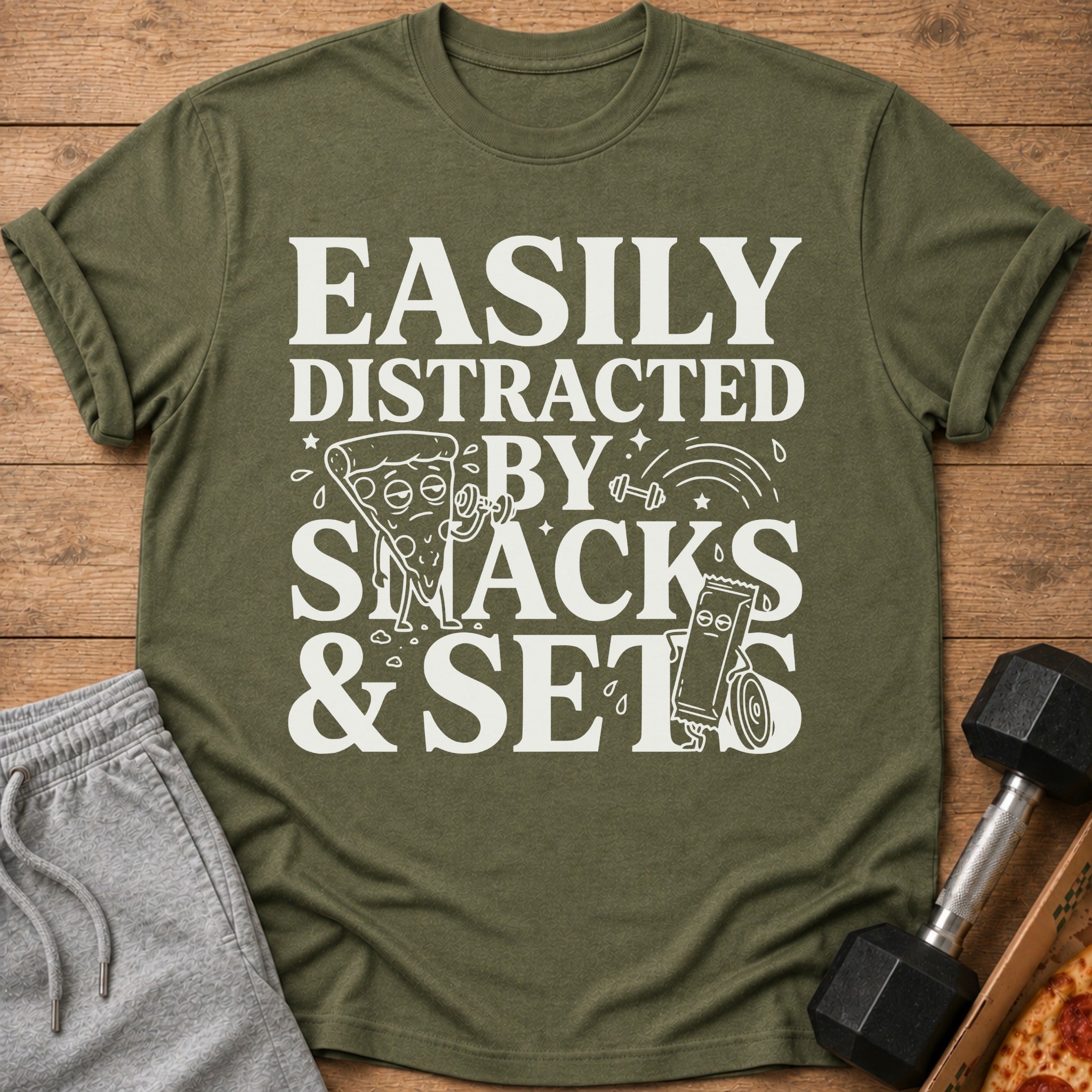 Olive green t-shirt with "Easily Distracted By Snacks & Sets" graphic.