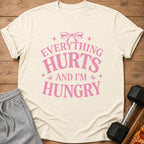Cream t-shirt with pink text "Everything Hurts And I'm Hungry"