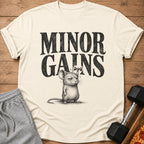 Cream t-shirt with "MINOR GAINS" text and a mouse lifting a dumbbell.