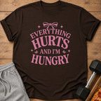 Brown t-shirt with pink text that says "Everything Hurts And I'm Hungry".