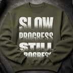 Olive green sweatshirt with distressed white text "SLOW PROGRESS STILL PROGRESS".