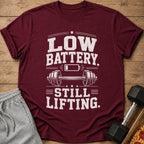 Maroon t-shirt with "LOW BATTERY. STILL LIFTING." text and barbell graphic.