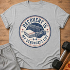 Grey t-shirt graphic with text "Recovery is my strongest lift. Rest reps count."