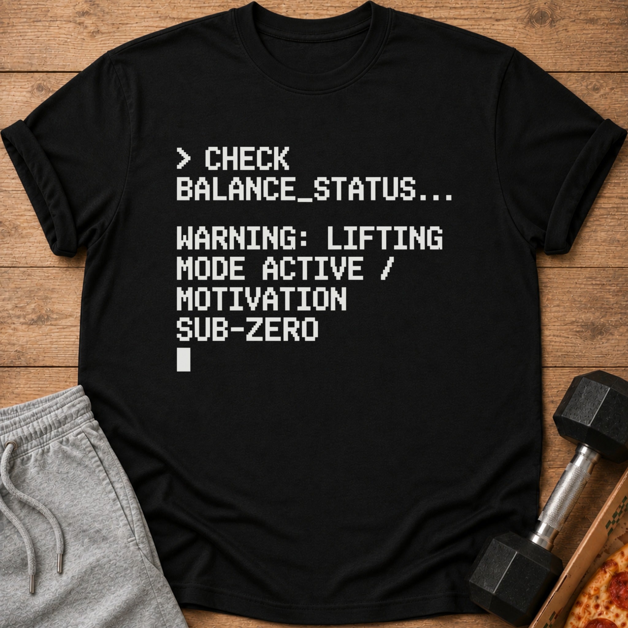 Black t-shirt with text: "CHECK BALANCE_STATUS... WARNING: LIFTING MODE ACTIVE / MOTIVATION SUB-ZERO"