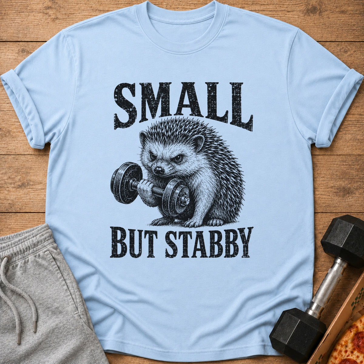 Light blue t-shirt with a hedgehog lifting a dumbbell and text "SMALL BUT STABBY".