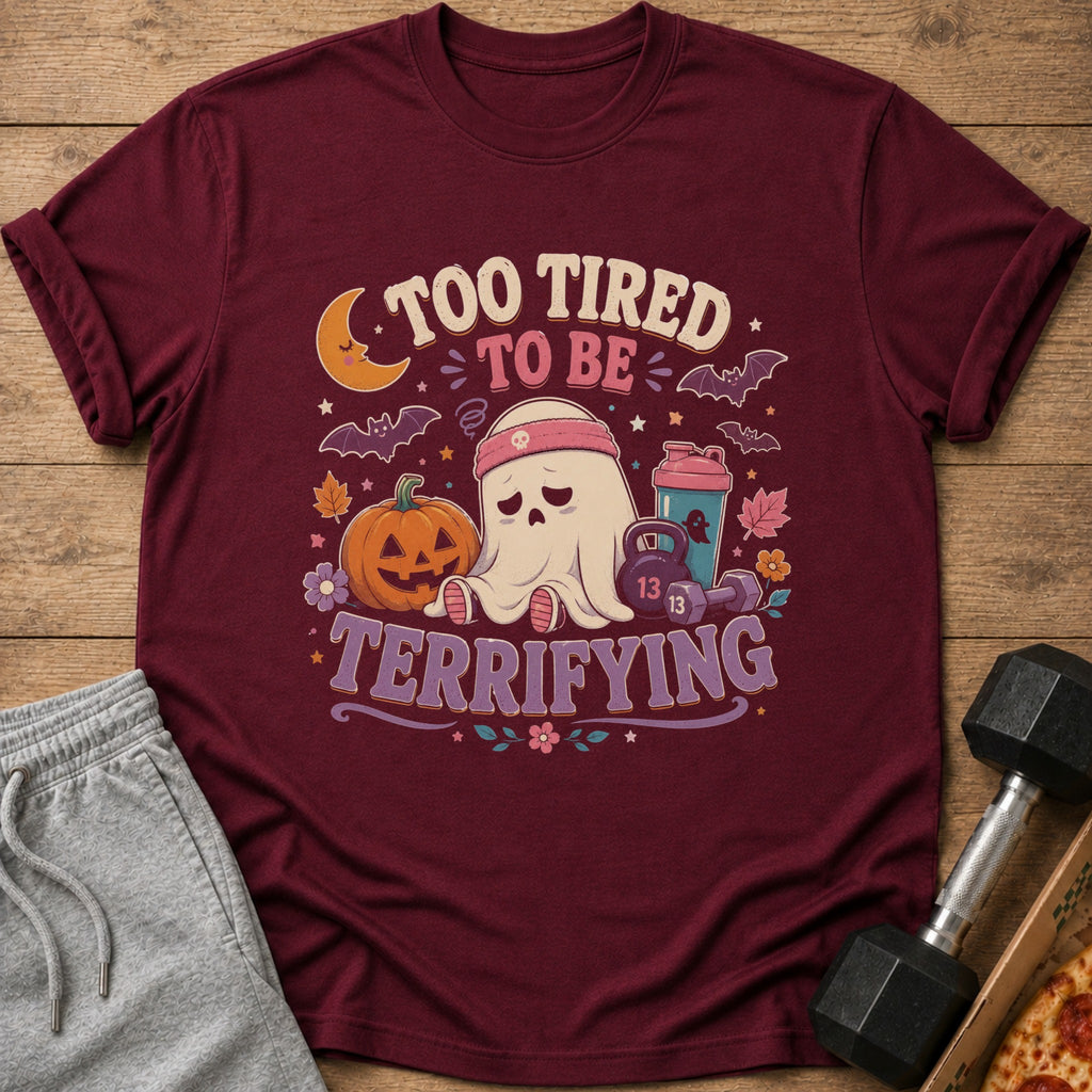 Maroon t-shirt with a ghost, pumpkin, and weights, reading "Too tired to be terrifying."