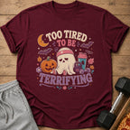 Maroon t-shirt with a ghost, pumpkin, and weights, reading "Too tired to be terrifying."