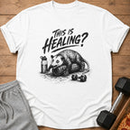T-shirt with opossum on foam roller and "This is Healing?" text.