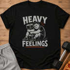 Black t-shirt with distressed graphic of a person hugging a dumbbell, text reads "HEAVY FEELINGS".