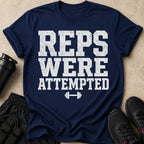 Navy t-shirt with white distressed text reading "REPS WERE ATTEMPTED" and a dumbbell graphic.