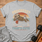 T-shirt graphic with sloth on weight bench, text "PROGRESS? YEAH... THAT'S CUTE"
