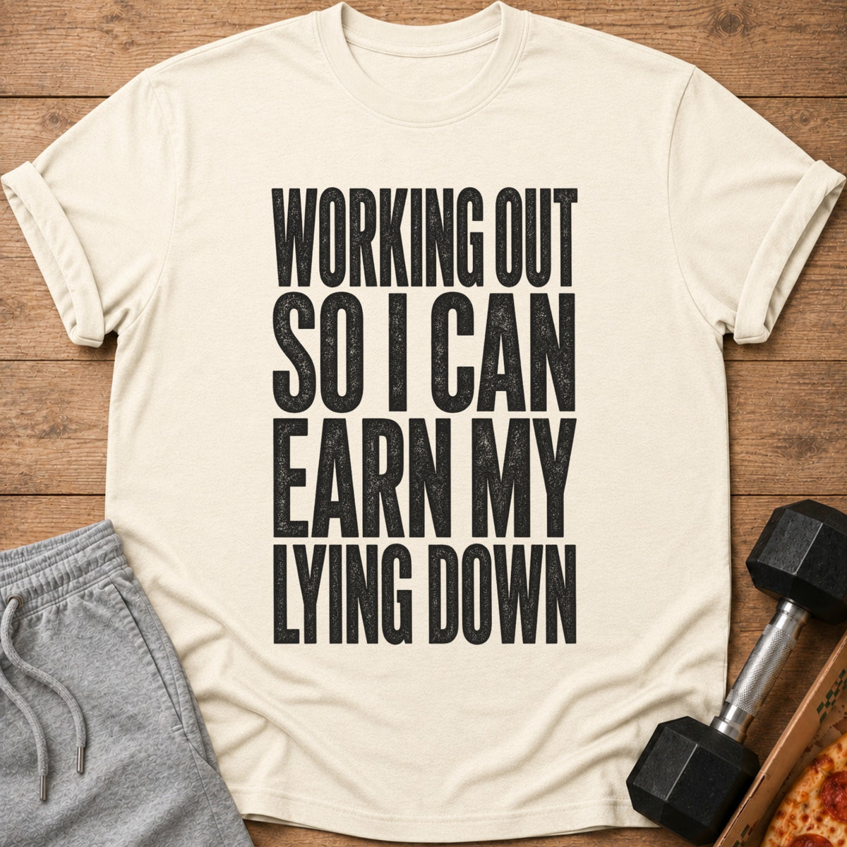 Light tan t-shirt with black text: "Working out so I can earn my lying down."