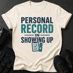 Cream t-shirt with text "PERSONAL RECORD IN SHOWING UP" and fitness icons.