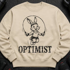 Light tan sweatshirt with a black graphic of a cartoon rabbit jump roping and the word OPTIMIST.
