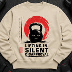 Cream sweatshirt with a black kettlebell design and text "LIFTING IN SILENT DISAPPROVAL".