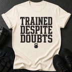Cream t-shirt with black text "TRAINED DESPITE DOUBTS" and kettlebell graphic.