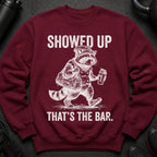 Maroon sweatshirt with graphic of a raccoon in gym clothes carrying a bag and shaker bottle.