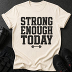 Cream t-shirt with distressed black text reading "STRONG ENOUGH TODAY" and a barbell graphic.
