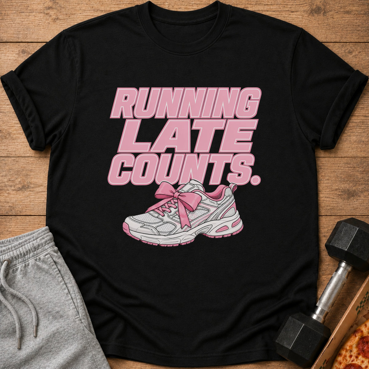 Black t-shirt with "RUNNING LATE COUNTS." text and a pink bow on a shoe.