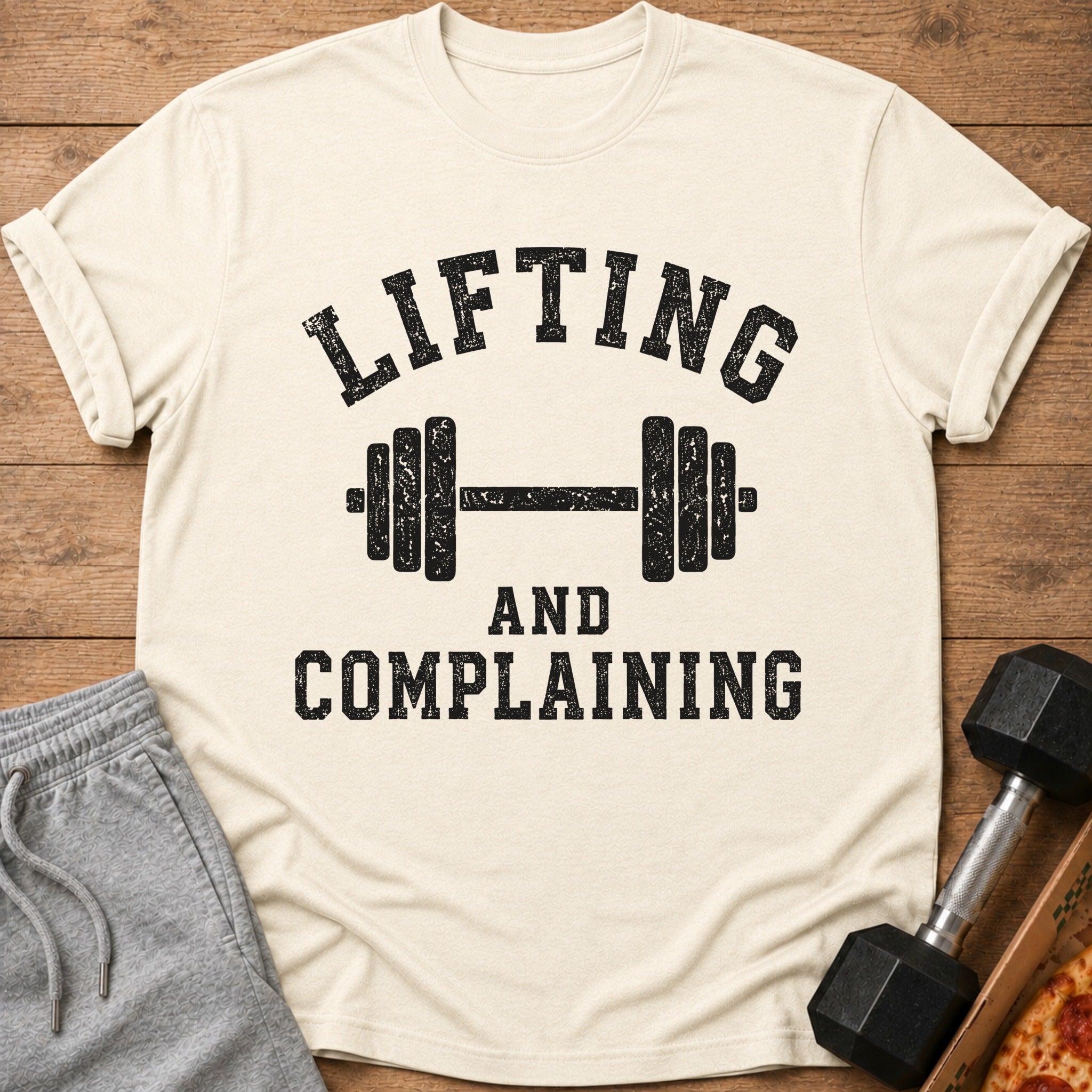Cream t-shirt with black text "LIFTING AND COMPLAINING" and barbell graphic.