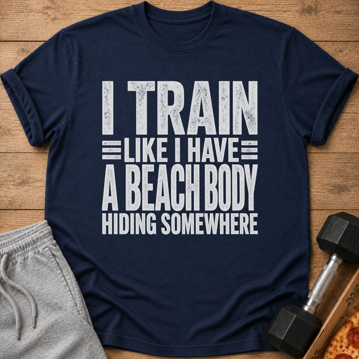 Navy t-shirt with white distressed text "I TRAIN LIKE I HAVE A BEACH BODY HIDING SOMEWHERE".
