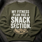 Olive green sweatshirt with white text about fitness and snacks.