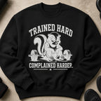 Black sweatshirt with skunk lifting weights and text "TRAINED HARD COMPLAINED HARDER."
