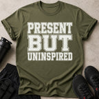 Olive green t-shirt with white distressed text reading "PRESENT BUT UNINSPIRED".
