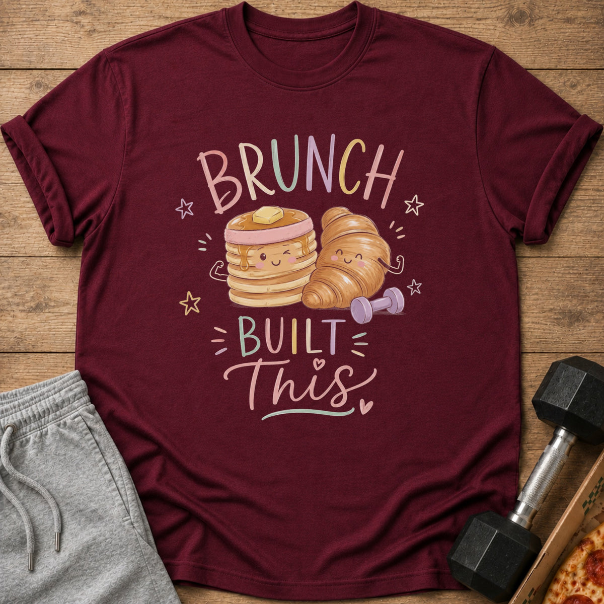 Maroon t-shirt with cartoon pancakes and croissant flexing, text says "Brunch Built This".
