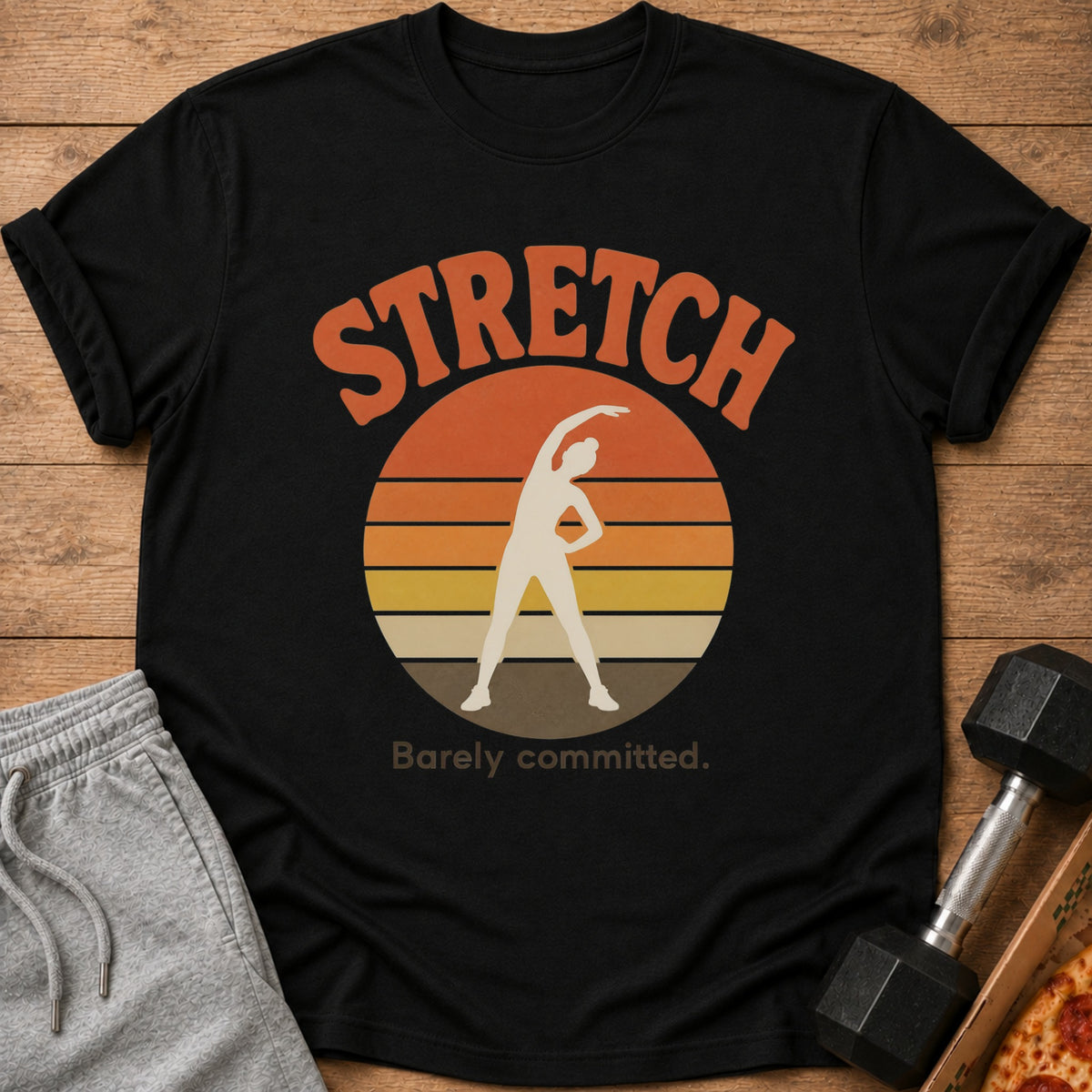 Black t-shirt with "STRETCH Barely committed" text and a sunset graphic.