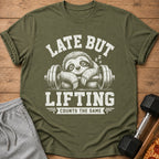 Olive green t-shirt with a sloth graphic and text "LATE BUT LIFTING COUNTS THE SAME".