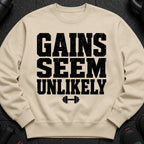 Beige sweatshirt with black text and dumbbell graphic: "GAINS SEEM UNLIKELY"