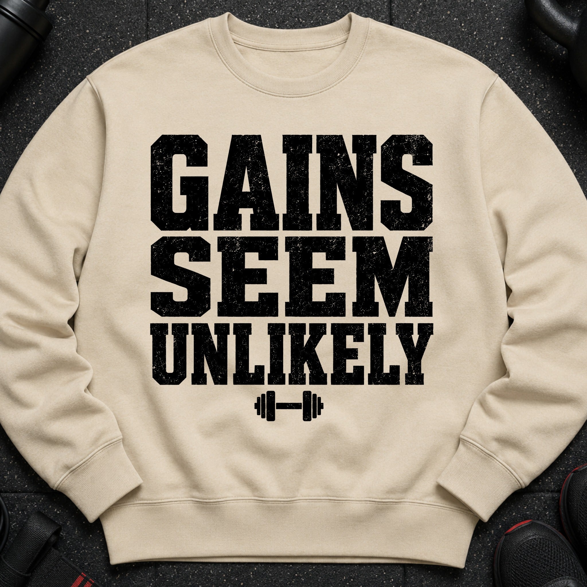 Beige sweatshirt with black text and dumbbell graphic: "GAINS SEEM UNLIKELY"