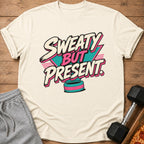 Cream t-shirt with "Sweaty But Present" text in retro style, dumbbell, and pizza slice.
