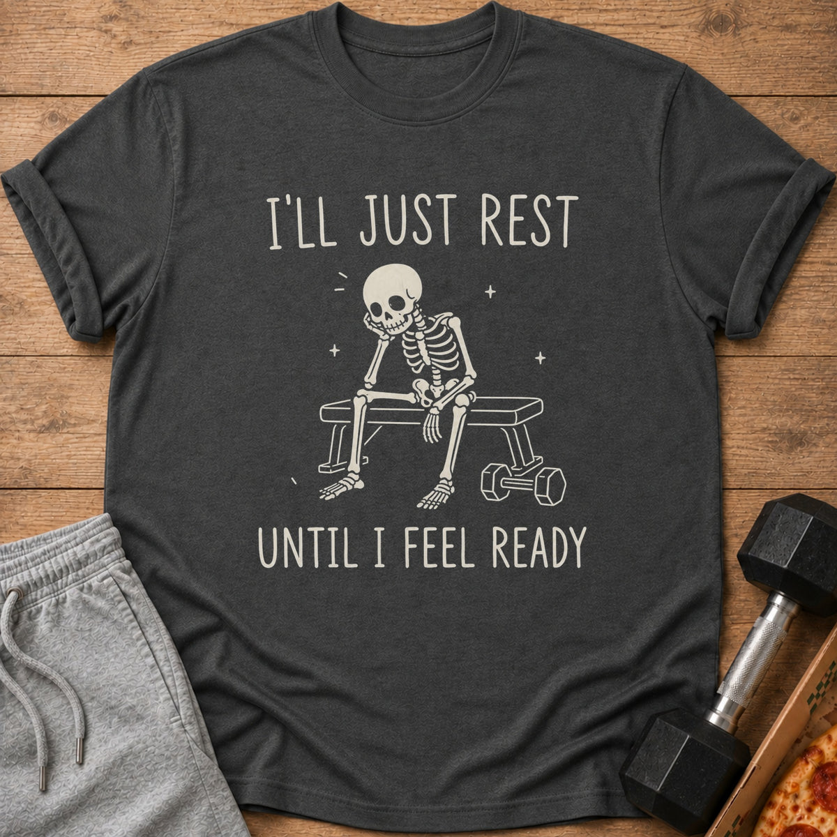 Dark gray t-shirt with skeleton sitting on a bench, reading "I'LL JUST REST UNTIL I FEEL READY".