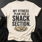 Cream t-shirt with "MY FITNESS PLAN HAS A SNACK SECTION" text and snacks.