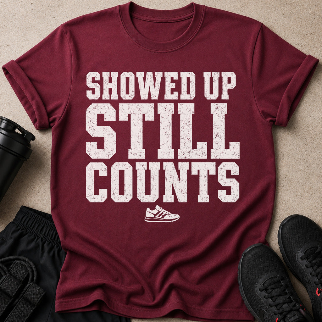 Maroon t-shirt with white text "SHOWED UP STILL COUNTS" and a shoe graphic.