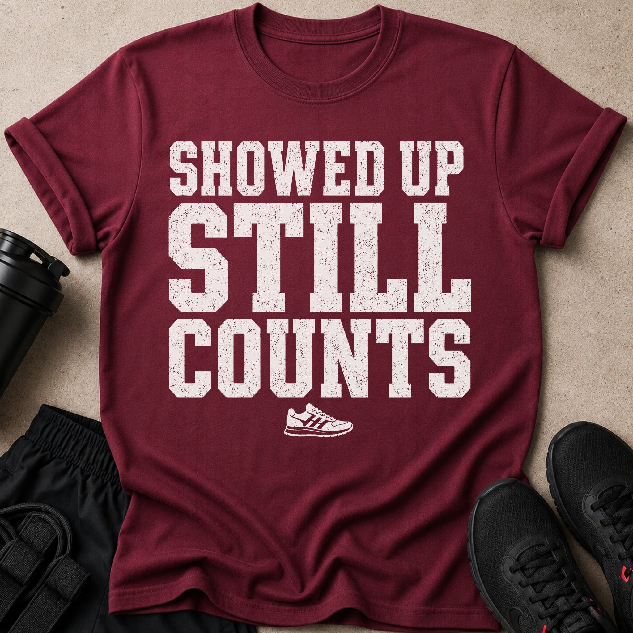 Maroon t-shirt with white text "SHOWED UP STILL COUNTS" and a shoe graphic.