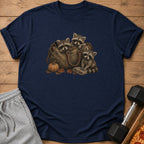 Three raccoons peeking out of a duffel bag with pumpkin and autumn leaves.
