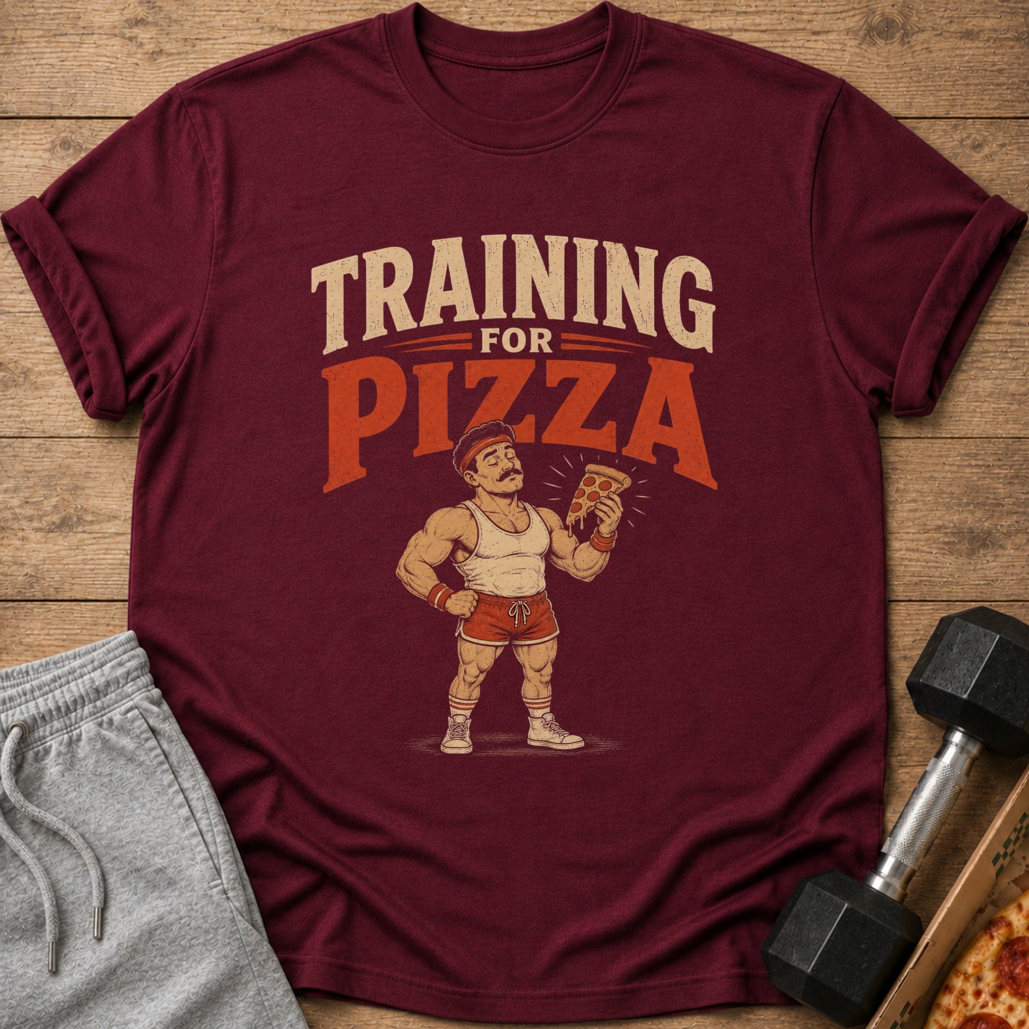 Maroon t-shirt with "Training For Pizza" text and a cartoon bodybuilder holding pizza.