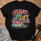 Black t-shirt with retro graphic: flamingo on inner tube, text "FLOAT NOW LIFT LATER".