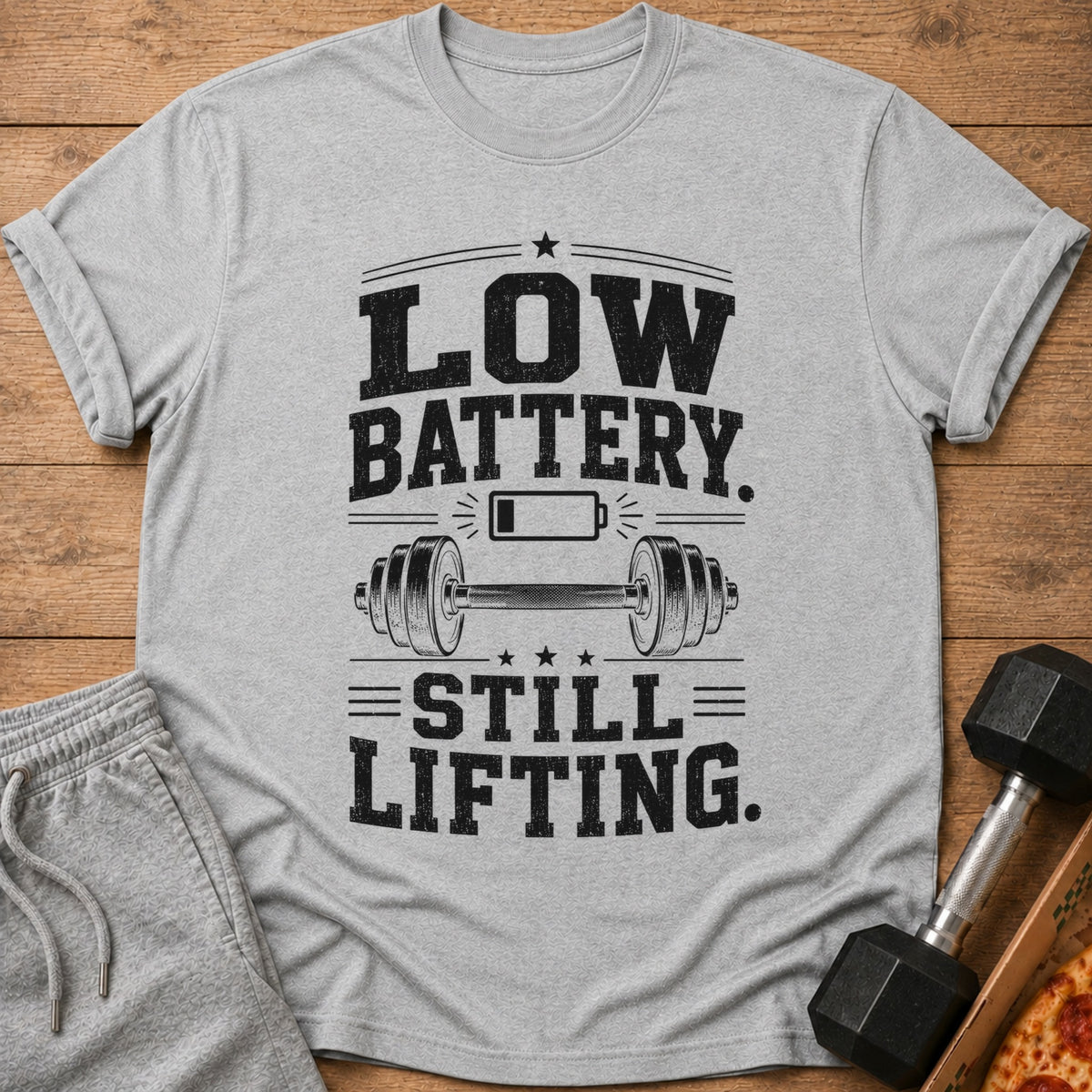 Grey t-shirt with "Low Battery. Still Lifting." text and a barbell graphic.