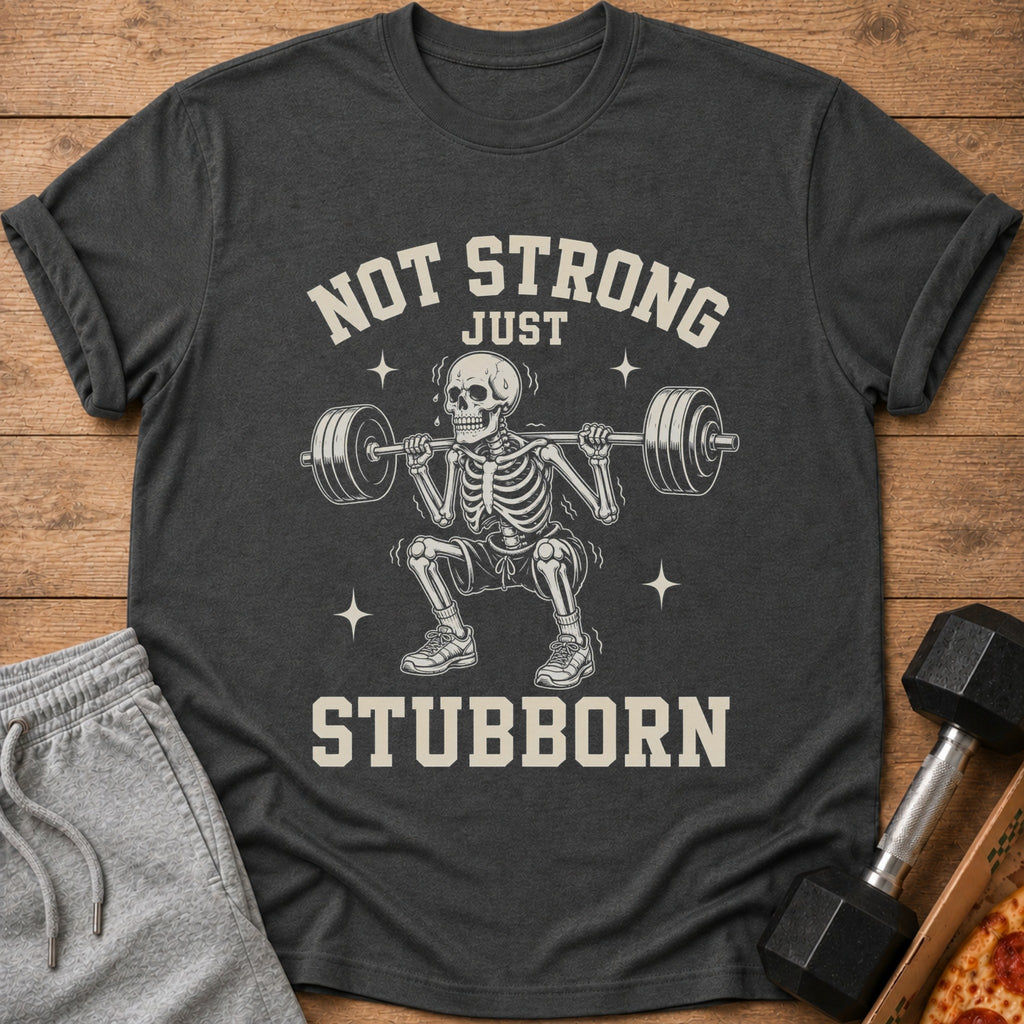 Dark grey t-shirt with skeleton lifting weights and text "NOT STRONG JUST STUBBORN".