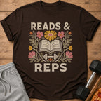 Brown t-shirt featuring a floral graphic with an open book, a dumbbell, and the text Reads & Reps.