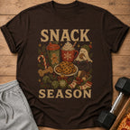 T-shirt with "SNACK SEASON" text and holiday-themed illustrations of cookies, drinks, and festive items.