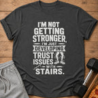 Dark gray t-shirt with white text about developing trust issues with stairs.