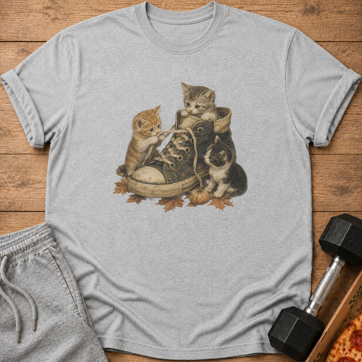 Three kittens playing with a shoelace inside a worn sneaker on autumn leaves.